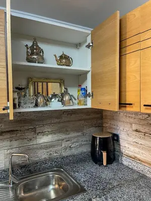 a kitchen with a sink and some wooden cabinets at Appartement bord de mer avec piscine à Bouznika in Bouznika