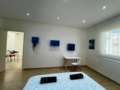 a bedroom with a bed and a room with a table at Cozy & Stylish 2BR - Near Arribat Center Mall in Rabat