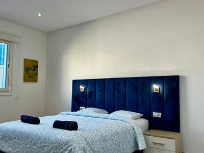 a bedroom with two beds and a blue headboard at Cozy & Stylish 2BR - Near Arribat Center Mall in Rabat