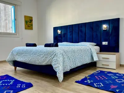 a bedroom with a large bed with a blue headboard at Cozy & Stylish 2BR - Near Arribat Center Mall in Rabat
