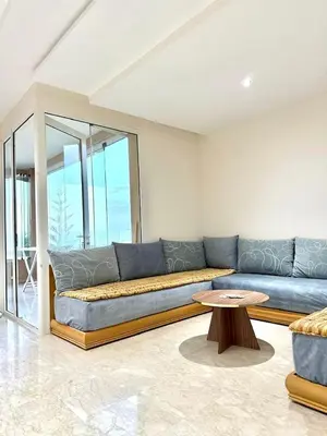 a living room with a blue couch and a table at Evasion apartment with beach and pool views in Bouznika