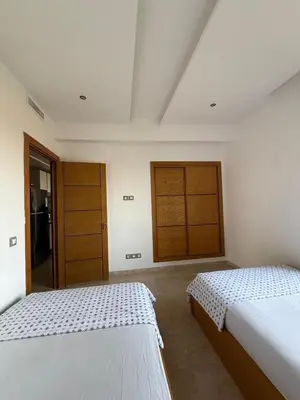 two beds in a white room with two doors at Evasion apartment with beach and pool views in Bouznika