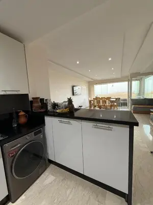 a kitchen with a washing machine and a counter top at Evasion apartment with beach and pool views in Bouznika