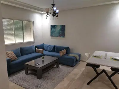 a living room with a blue couch and a table at Central Park in Mohammedia