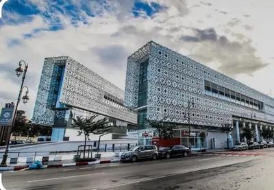 a building with two towers with cars parked in front of it at Elégance &Confort Agdal in Rabat