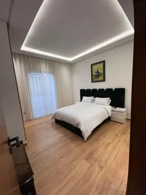 a bedroom with a white bed and a wooden floor at Luxury apartment in Rabat