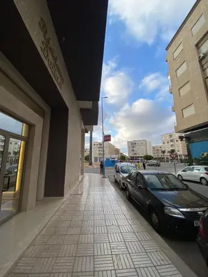 a building with cars parked on the side of a sidewalk at AFCON near rabat complex de football in Bouznika