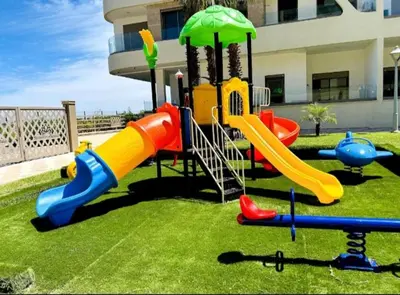 a playground with a slide in the grass at Garden paradis bouznika in Bouznika