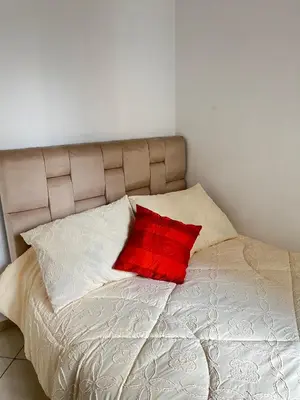 a bed with a red pillow on top of it at Zenata Family Apartment in Aïn Harrouda
