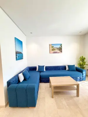 a living room with a blue couch and a coffee table at Charmante maison de vacances proche de la plage à quelques minutes de Rabat in Temara