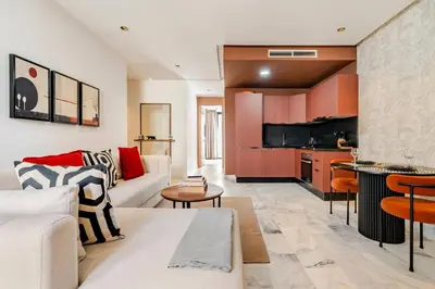 a living room with a couch and a kitchen at Appartement Design avec Parking et Salle de Sport Ferme Bretonne in Casablanca