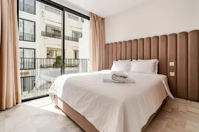 a bedroom with a large bed and a large window at Appartement Design avec Parking et Salle de Sport Ferme Bretonne in Casablanca