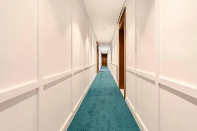 a hallway with white walls and a green carpet at Appartement Design avec Parking et Salle de Sport Ferme Bretonne in Casablanca