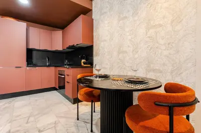 a kitchen with pink cabinets and a table and chairs at Appartement Design avec Parking et Salle de Sport Ferme Bretonne in Casablanca