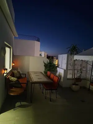 a table and chairs on a balcony at night at 2 min walk from Four Seasons Hotel-Cozy Terrace Stay in the Heart of Rabat in Rabat