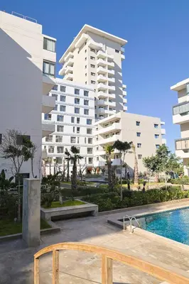 a swimming pool in front of a large building at Studio Cosy avec Piscine & proche de la plage in Aïn Harrouda