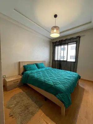 a bedroom with a bed with a green comforter and a window at Mohemmadia in Mohammedia