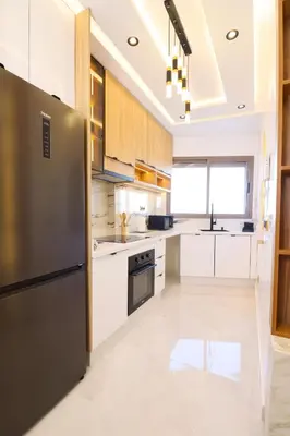 a kitchen with white cabinets and a stainless steel refrigerator at Le Nour- 2 modern bedrooms Luxury and Comfort in Bouznika