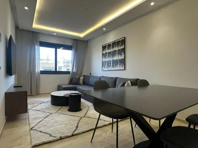 a living room with a table and a couch at Appartement 1BR Prestige & Confort à Hay Riad in Rabat