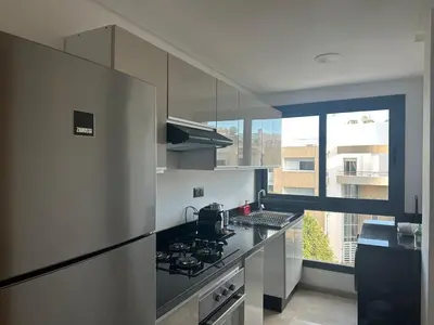 a kitchen with a refrigerator and a stove top oven at Appartement 1BR Prestige & Confort à Hay Riad in Rabat