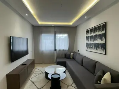 a living room with a couch and a table at Appartement 1BR Prestige & Confort à Hay Riad in Rabat