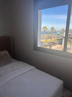 a bedroom with a window with a view of a beach at Appartement neuf vue mer sur la corniche in Rabat