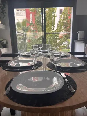 a wooden table with plates and wine glasses on it at Appartement neuf vue mer sur la corniche in Rabat