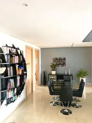 a living room with a table and chairs and a book shelf at Prestigia Luxurious 3BR 5 min walk from stadium in Rabat