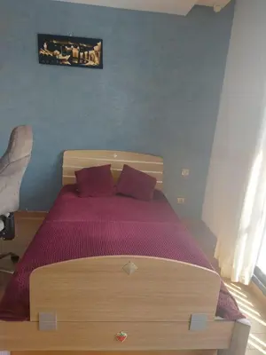 a bedroom with a wooden bed with purple sheets at Prestigia Luxurious 3BR 5 min walk from stadium in Rabat