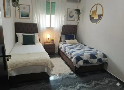 a bedroom with two beds and a mirror at Appartement dans le centre de la plage de av Tantan in Casablanca