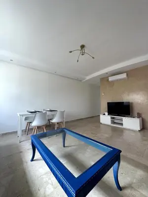 a living room with a blue table and a tv at La Perle Aïn Diab Beachfront in Casablanca
