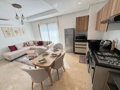 a kitchen and living room with a table and chairs at VIVASTAY Casablanca - Zenata eco city beach access with swimming pool in Aïn Harrouda