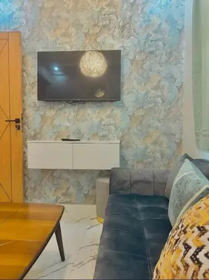 a living room with a couch and a tv on a wall at Najia Blue Pearl in Sidi Rahal