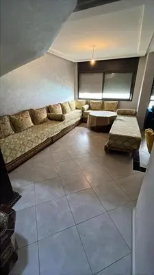 a living room with a couch and a table at Appartement duplexe convivial in Bouznika