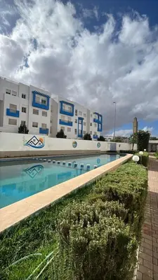 a large building with a swimming pool in front of it at Appartement duplexe convivial in Bouznika