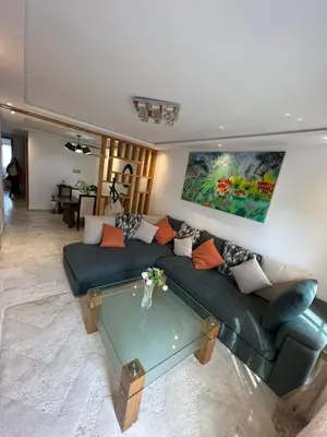 a living room with a green couch and a glass table at Appartement confortable in Maarif