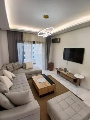 a living room with a couch and a flat screen tv at Cozy 2-bedroom apartment, pool view with beach access a Zenata City Eco Casablanca in Oulad Akkou