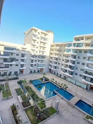 an apartment with a swimming pool in front of some buildings at Cozy 2-bedroom apartment, pool view with beach access a Zenata City Eco Casablanca in Oulad Akkou