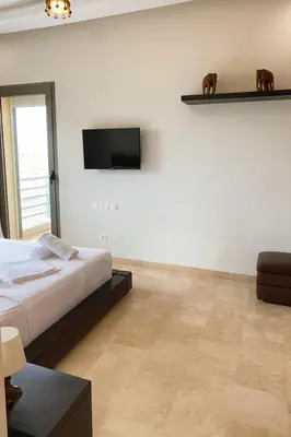 a bedroom with a bed and a television on a wall at Moroccan Sunset - Charming 3BR near Airport Med 5 in Nouaseur