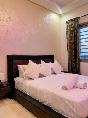 a bedroom with a bed with white sheets and pillows at Moroccan Sunset - Charming 3BR near Airport Med 5 in Nouaseur