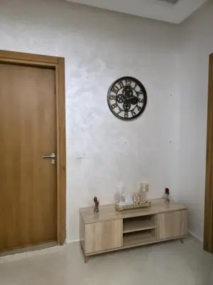 a clock on a wall next to a wooden cabinet at appartement luxe dt5 in Mohammedia