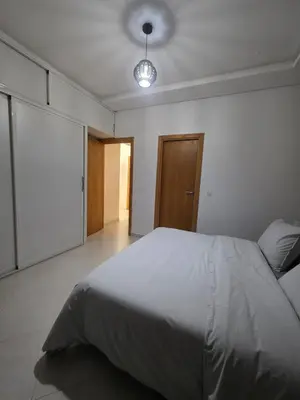 a bedroom with a large white bed and a light at appartement luxe dt5 in Mohammedia