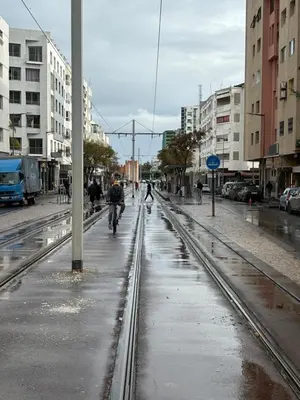 a wet city street with people riding bikes on it at Appartamento di lusso nel cuore di Rabat in Rabat