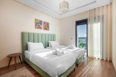 a bedroom with two beds and a large window at Luxury 2BR Pearl of Agdal Near Agdal Train Station in Rabat