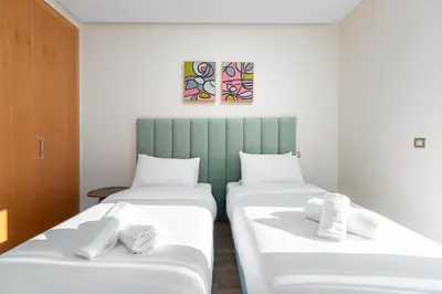 two beds in a room with white sheets at Luxury 2BR Pearl of Agdal Near Agdal Train Station in Rabat