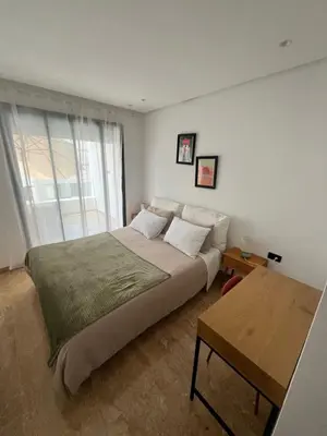 a bedroom with a large bed and a table at Apartment Dar Bouazza with swimming pools and 2 bedrooms in Casablanca