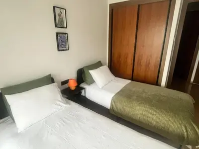 a bedroom with two beds and a wooden door at Apartment Dar Bouazza with swimming pools and 2 bedrooms in Casablanca