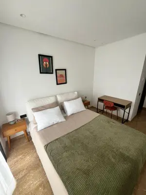 a bedroom with a large bed and a table at Apartment Dar Bouazza with swimming pools and 2 bedrooms in Casablanca