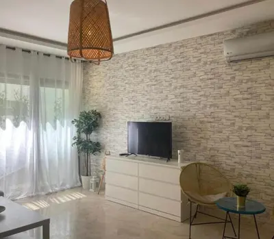 a living room with a tv on a brick wall at Cozy studio with terrace - Mohammedia Center in Mohammedia