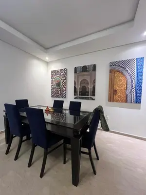 a dining room table and chairs in a room with paintings at Appartement spacieux tout confort in Casablanca